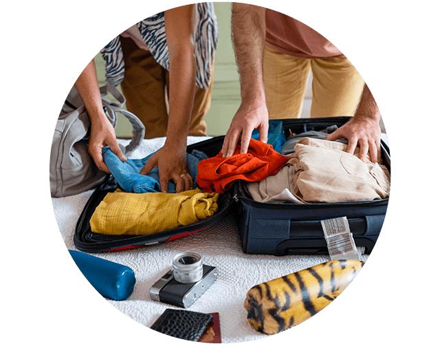 Twee mensen pakken een koffer in op bed met allerlei spullen uitgestald