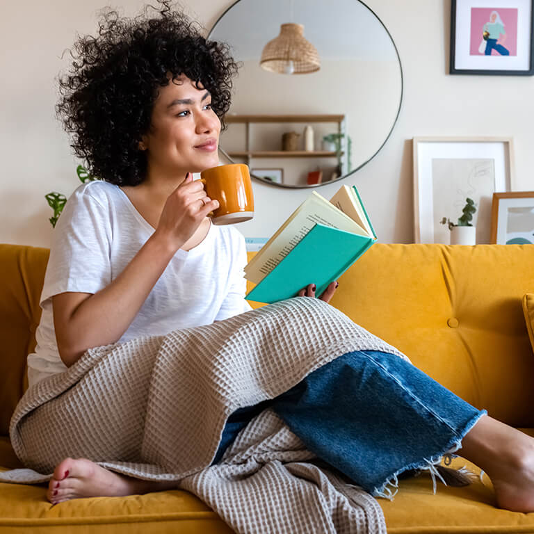 Vrouw leest boek met kop thee
