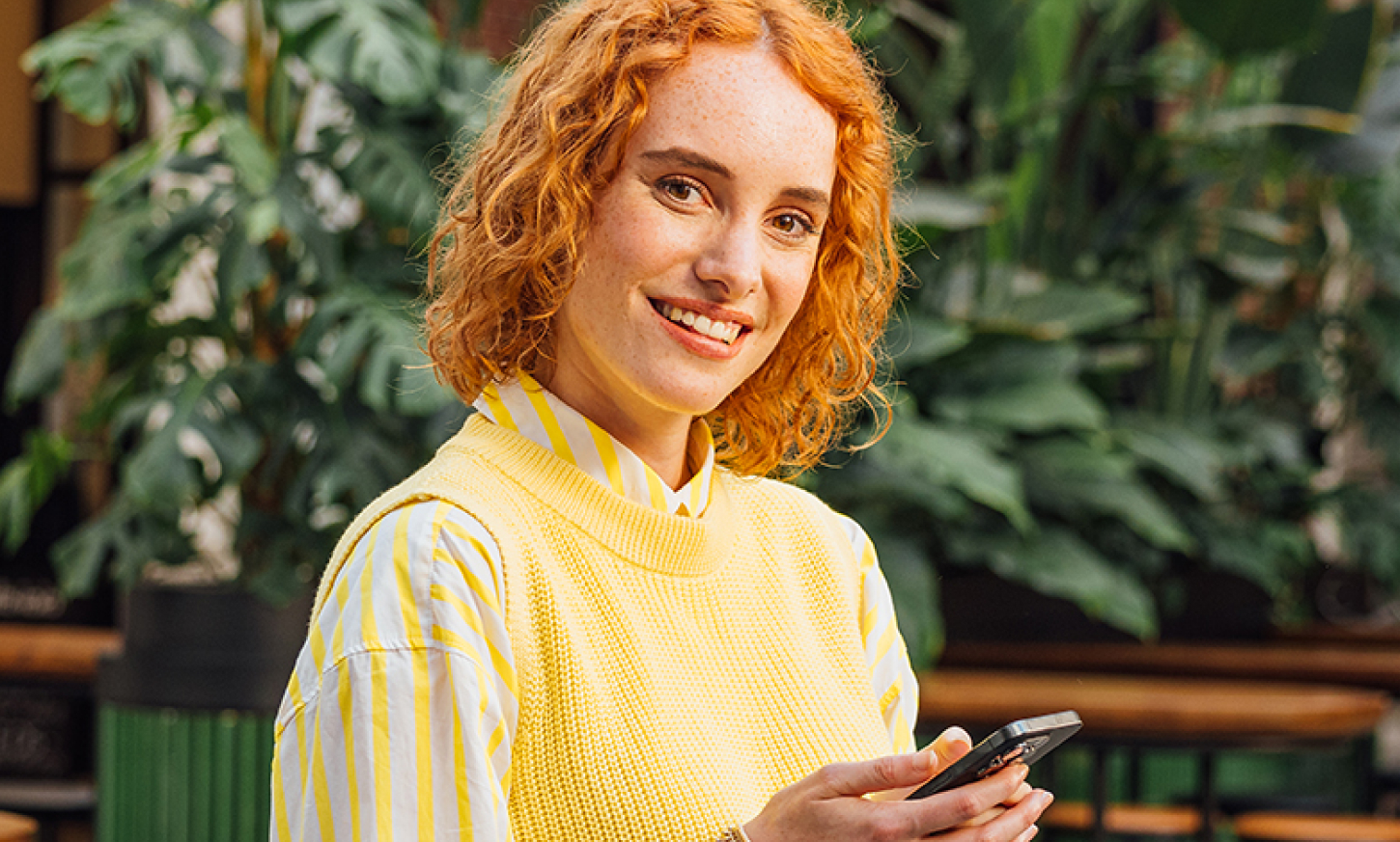 Jonge vrouw die lacht met mobiel in haar hand