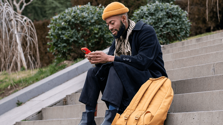 Man zit op trap met telefoon in hand